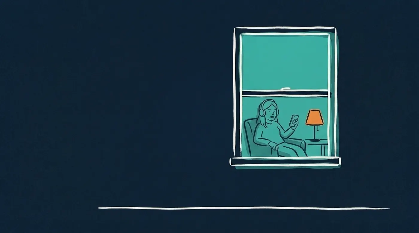 Een verlicht raam 's avonds: naast een oranje lamp zit een vrouw met een koptelefoon ontspannen in een fauteuil en praat in haar telefoon